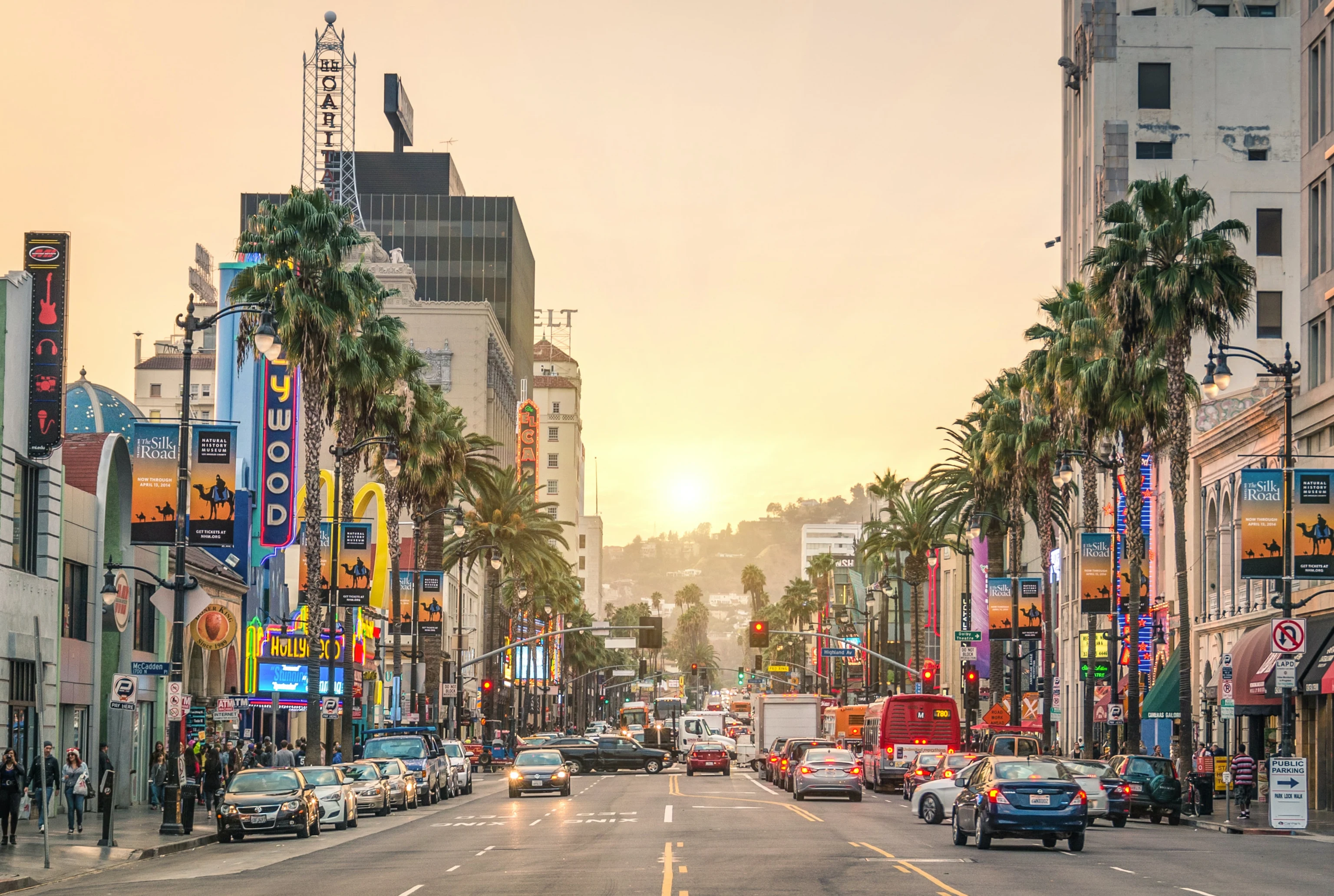 A palm-lined Los Angeles boulevard with traffic at sunset