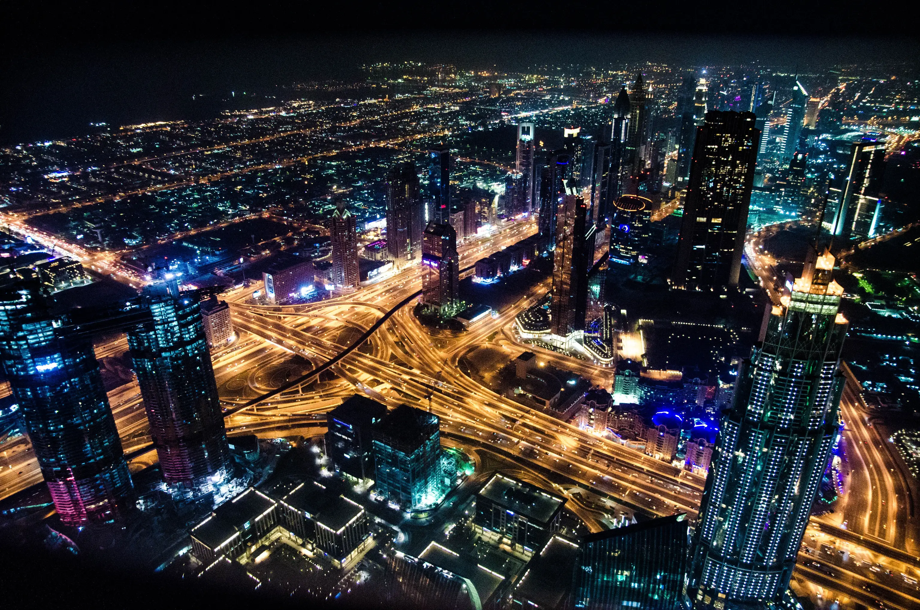 An aerial night view of a city with illuminated highways and skyscrapers