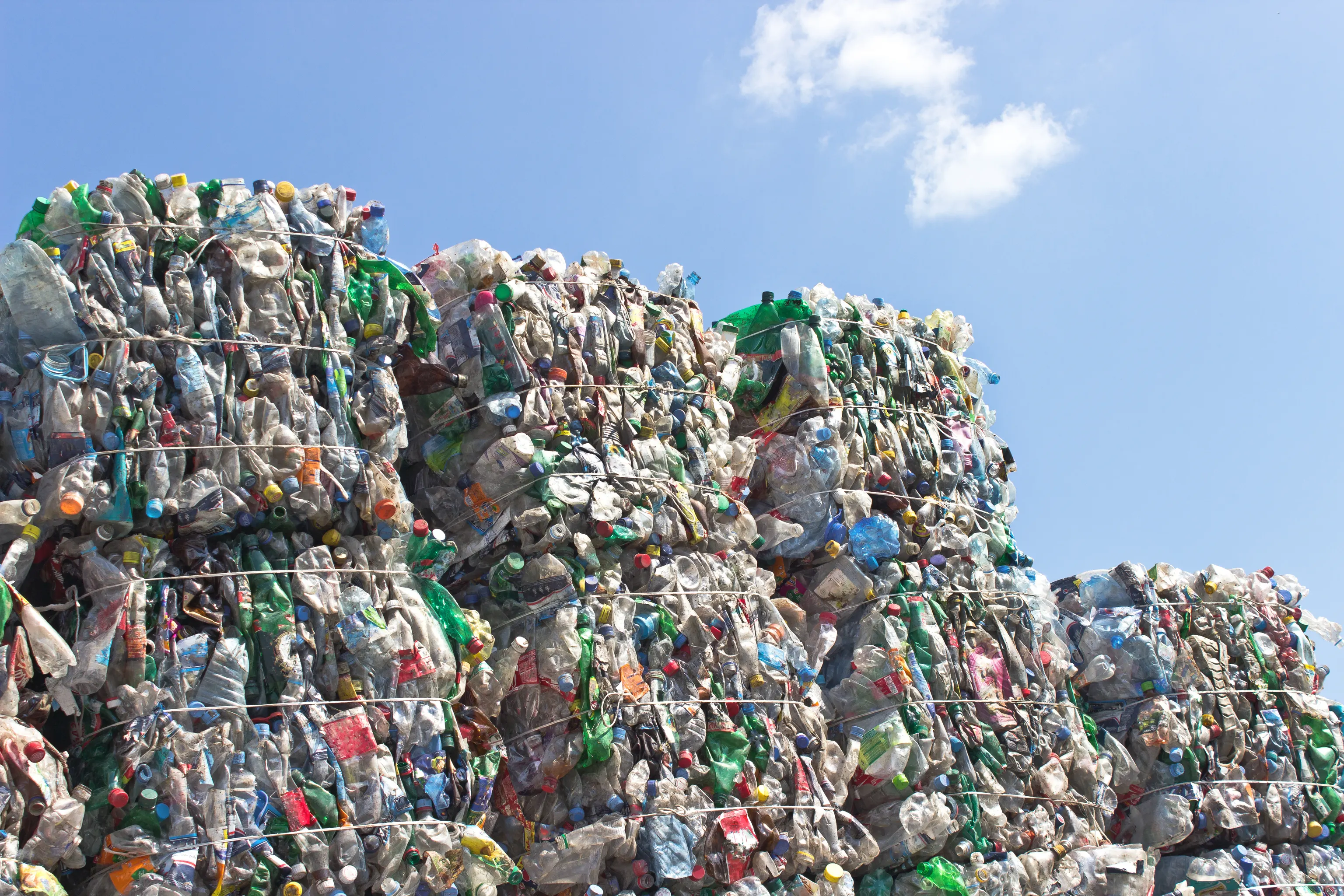 Bales of crushed plastic bottles stacked against a blue sky