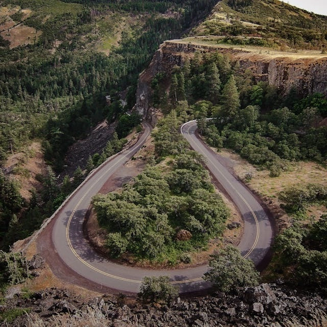 A road winding through a hairpin curve between forested cliffs