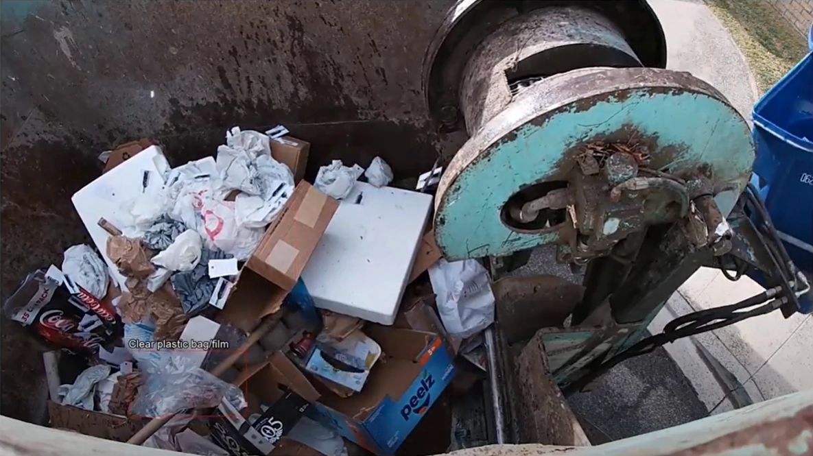 The same hopper image with a clear plastic bag flagged by Prairie Robotics' AI contamination detection