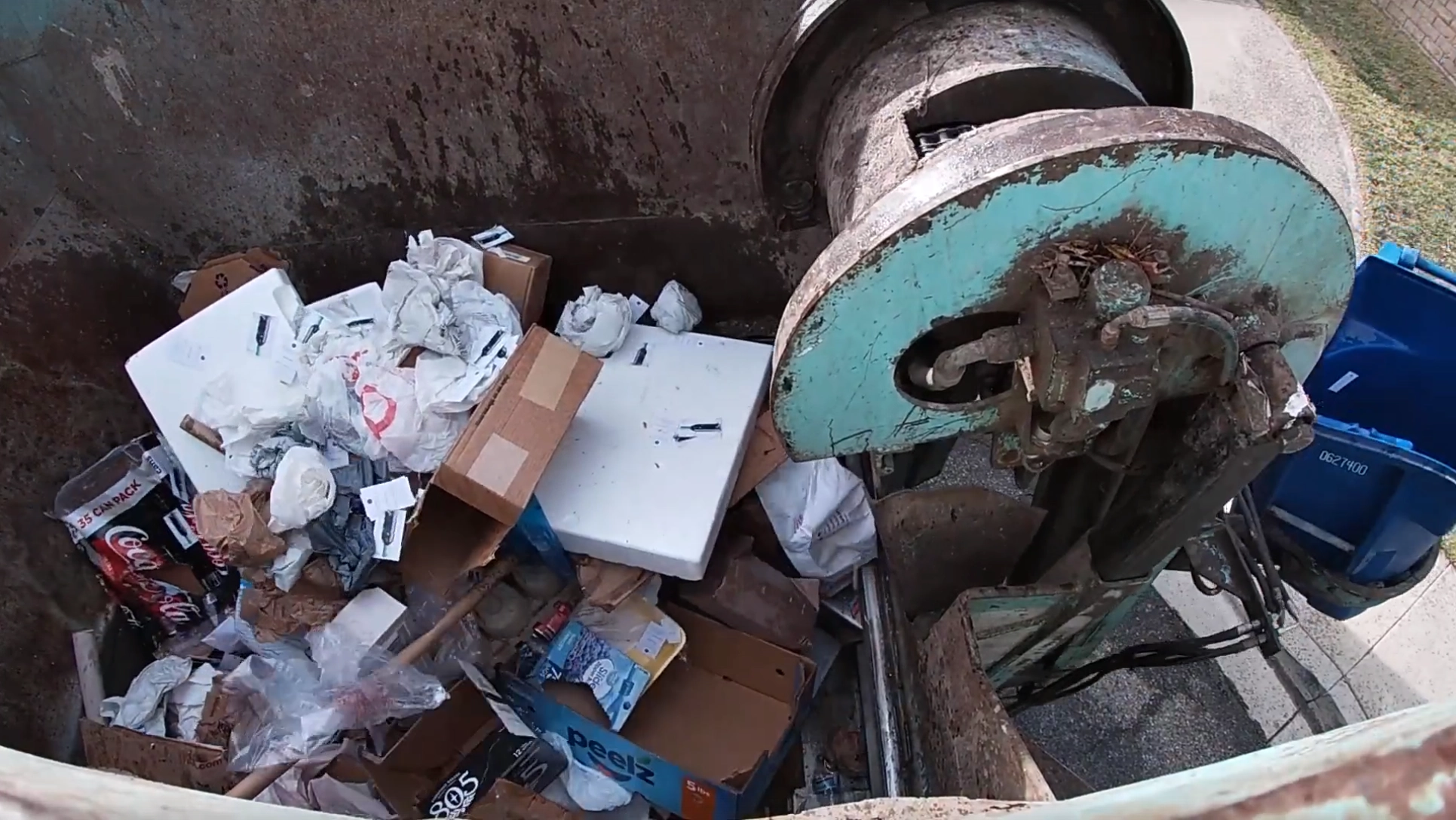 Camera view into a collection truck hopper full of recyclables mixed with plastic bags, Styrofoam and other contaminants