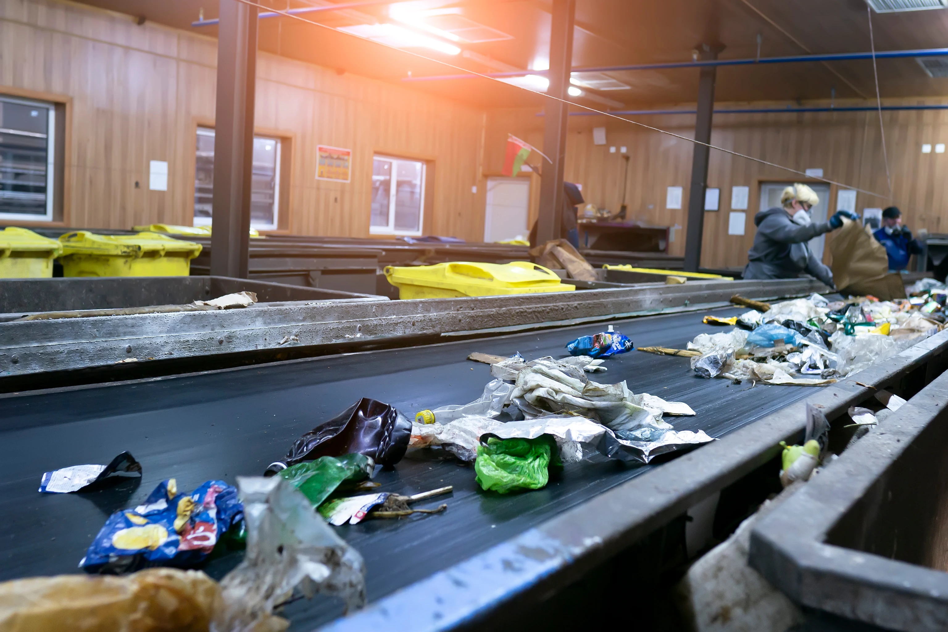 Mixed waste on a conveyor belt as a worker sorts material in a recycling facility