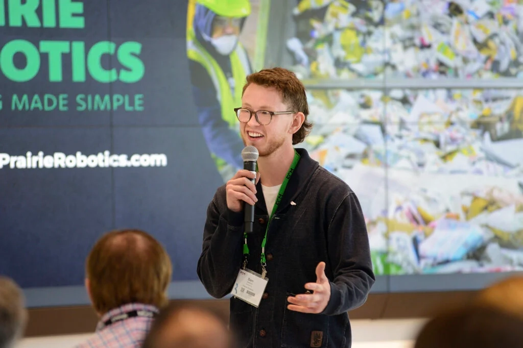 A Prairie Robotics team member speaking at a microphone in front of a Prairie Robotics presentation screen