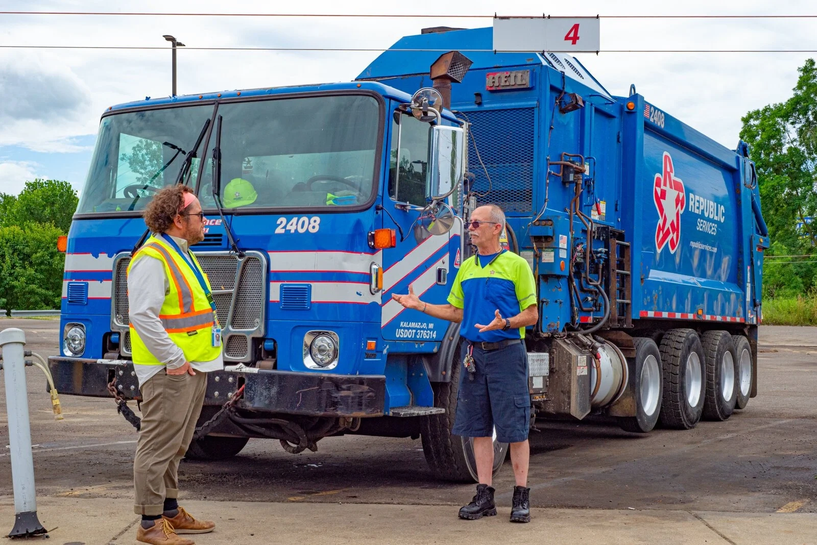 Two Kalamazoo recycling workers talking beside a blue Republic Services collection truck